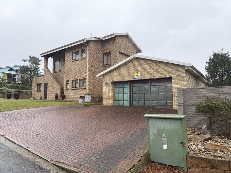 Front exterior view of a double-story brick house featuring a paved driveway, double garage, and an upper-level balcony.