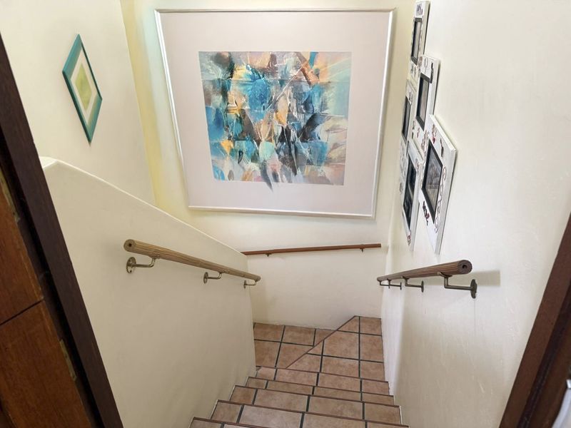 A staircase featuring tiled steps and dual wooden handrails, providing access between levels within the home.