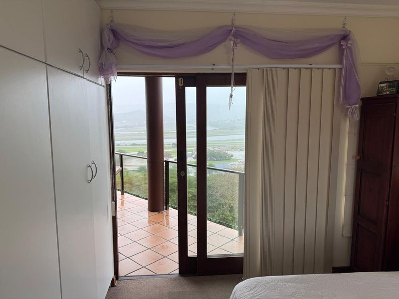 Bedroom featuring built-in cupboards and a sliding glass door providing direct access to a tiled balcony with scenic views.