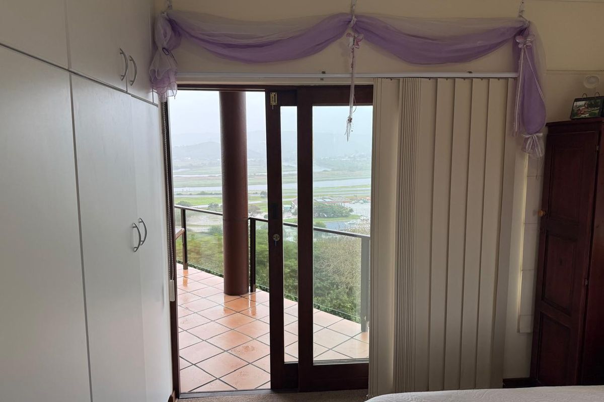 Bedroom featuring built-in cupboards and a sliding glass door providing direct access to a tiled balcony with scenic views.