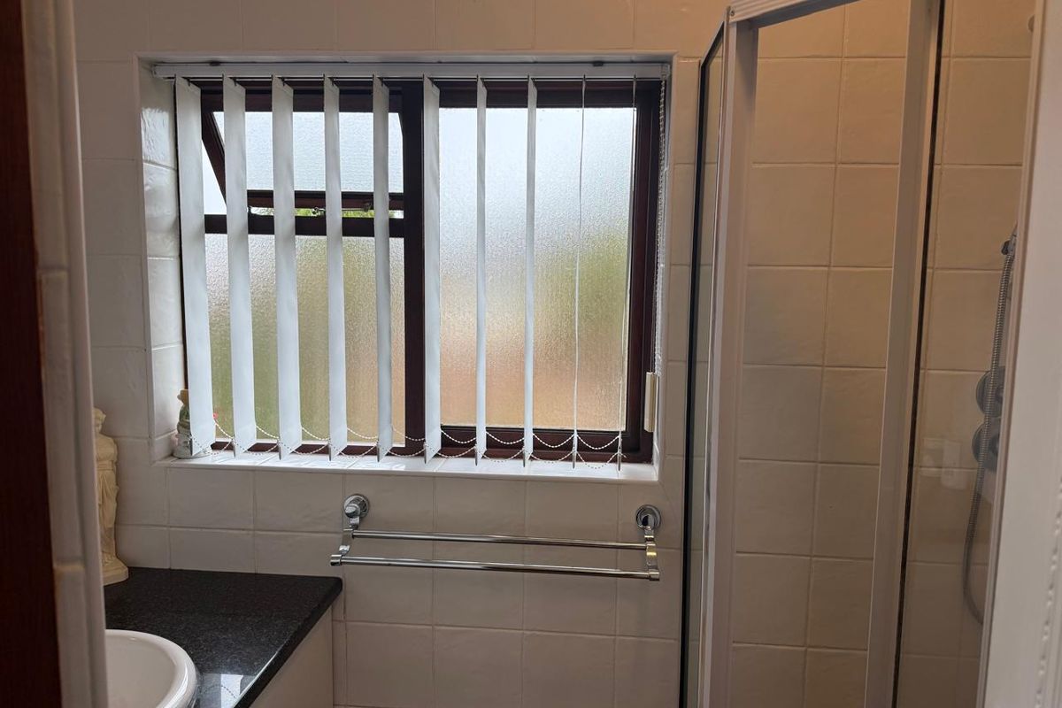 A functional bathroom featuring a shower enclosure, vanity cabinet with integrated basin, and tiled wall finishes.