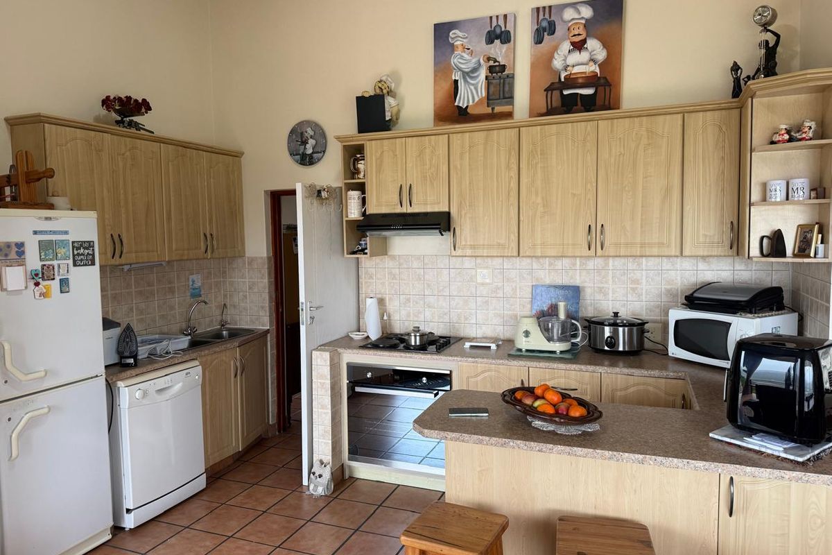 A functional kitchen featuring light wood-finish cabinetry, tiled backsplash, built-in oven with gas hob, and a breakfast nook area.
