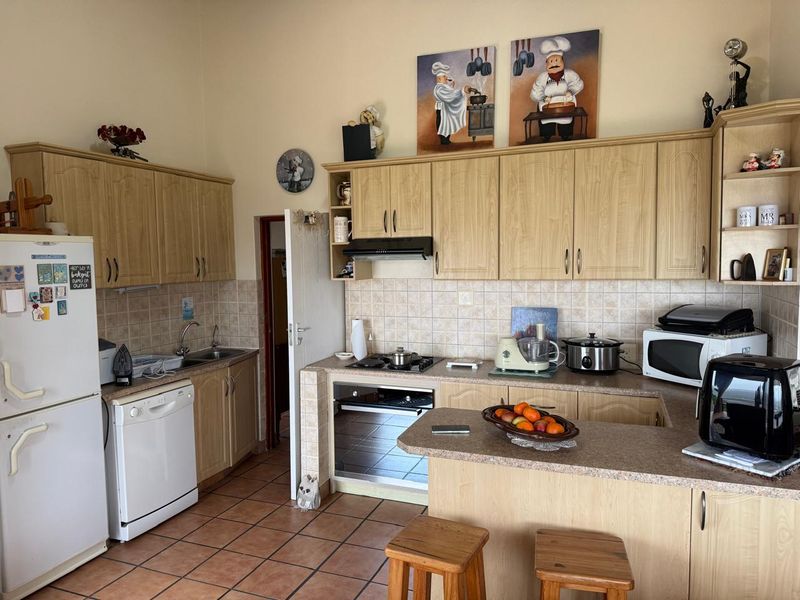 A functional kitchen featuring light wood-finish cabinetry, tiled backsplash, built-in oven with gas hob, and a breakfast nook area.