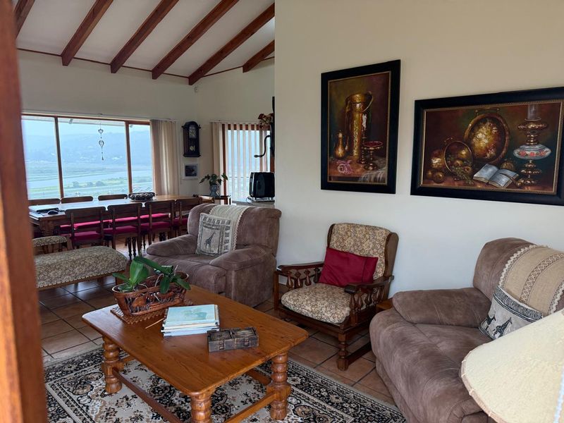 Spacious open-plan living and dining area featuring exposed timber ceiling beams, terracotta flooring, and large sliding doors with scenic views.