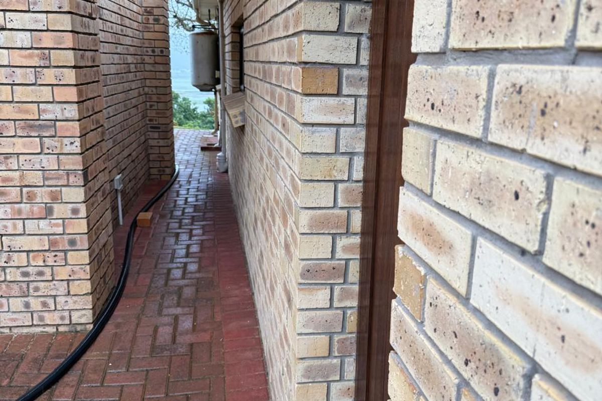 A narrow side passage featuring face brick walls and red paved flooring, providing access to the rear of the property.