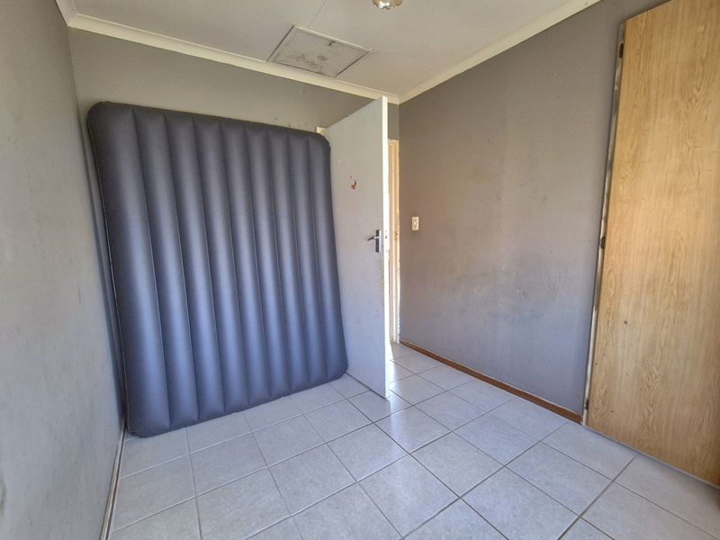A vacant bedroom featuring tiled flooring, a built-in cupboard, and neutral wall finishes, offering a blank canvas for potential interior updates.