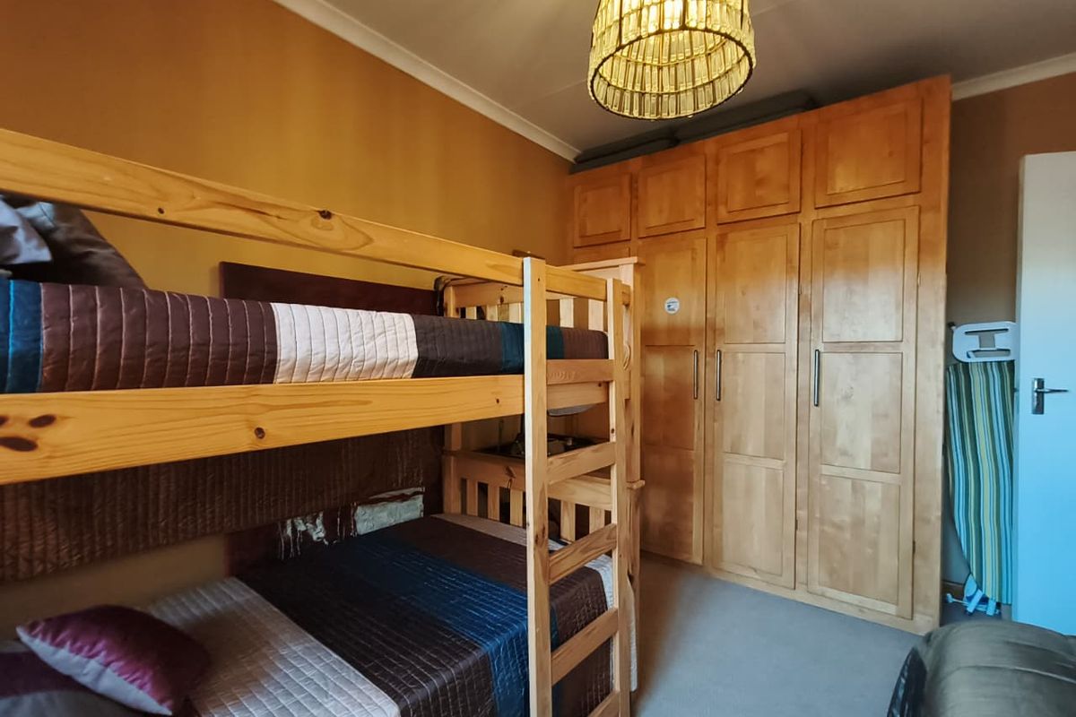 A bedroom featuring built-in wooden cupboards and carpeted flooring, providing functional storage space.