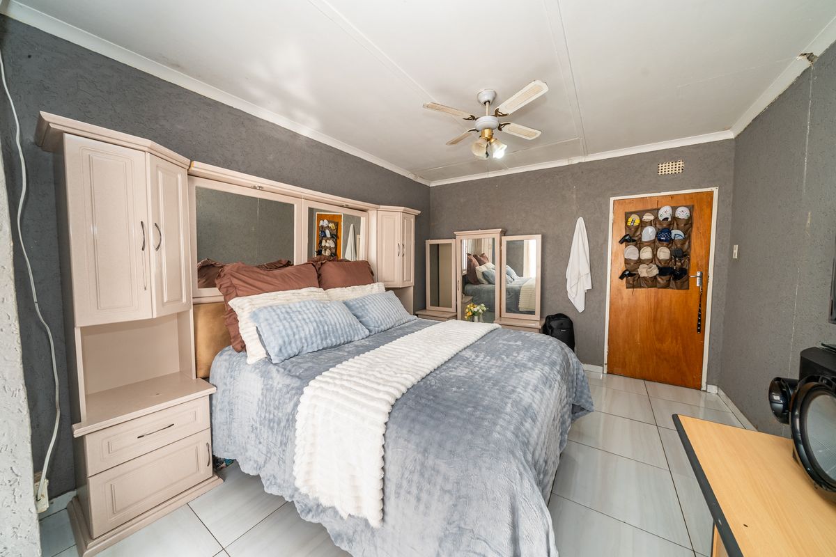A bedroom featuring tiled flooring, a ceiling fan, and built-in cabinetry with integrated mirrors.