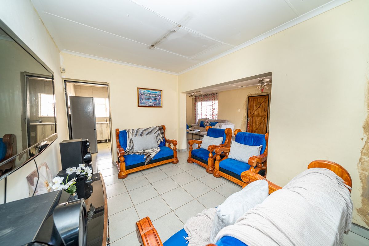 Living room featuring tiled flooring and direct access to the kitchen area, currently requiring cosmetic updates to the walls and ceiling.