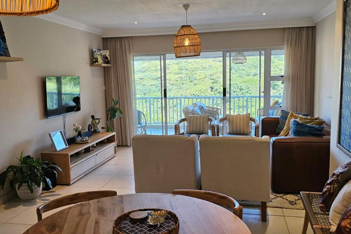 Spacious living room featuring tiled flooring, recessed lighting, and large sliding glass doors that open onto a balcony with scenic views.
