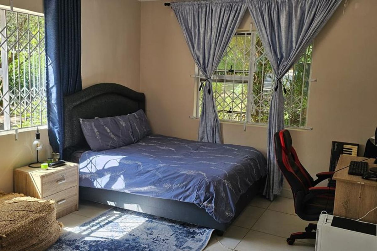 A functional bedroom featuring tiled flooring and windows fitted with security bars, providing natural light and ventilation.