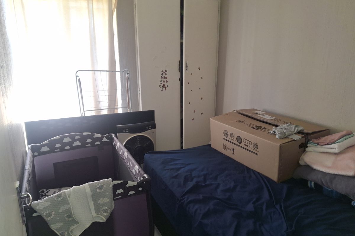 A bedroom featuring a built-in wardrobe, currently used as a multi-purpose space with various personal items.