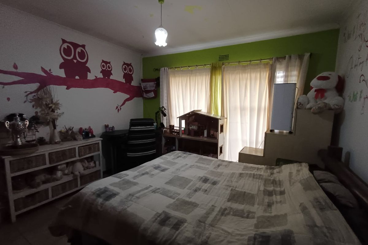 A bedroom featuring a ceiling light fixture and curtain rails, showing visible water staining on the ceiling.