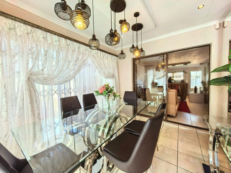 A bright dining area featuring tiled flooring, modern pendant lighting, and a sliding glass door providing access to the adjacent living space.