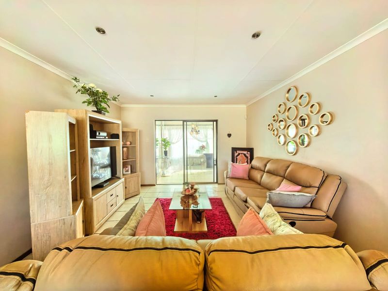 A comfortable living room featuring tiled flooring, recessed downlighting, and a sliding glass door providing access to the outdoor patio area.