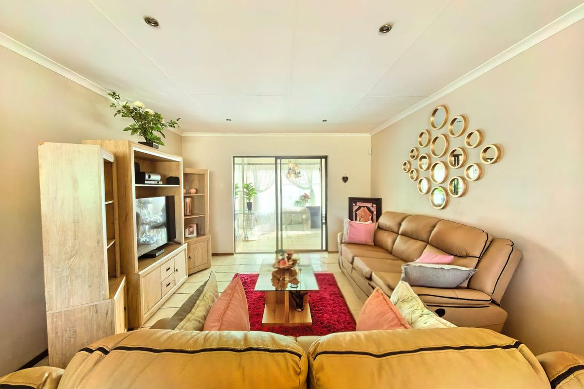 A comfortable living room featuring tiled flooring, recessed downlighting, and a sliding glass door providing access to the outdoor patio area.