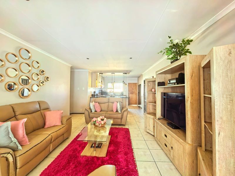 Open-plan living area featuring tiled flooring, recessed lighting, and a connected kitchen with a breakfast bar and cabinetry.