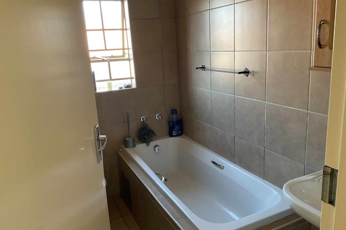 A functional bathroom featuring a built-in bathtub, tiled wall finishes, and a wall-mounted basin, providing a practical layout for daily use.
