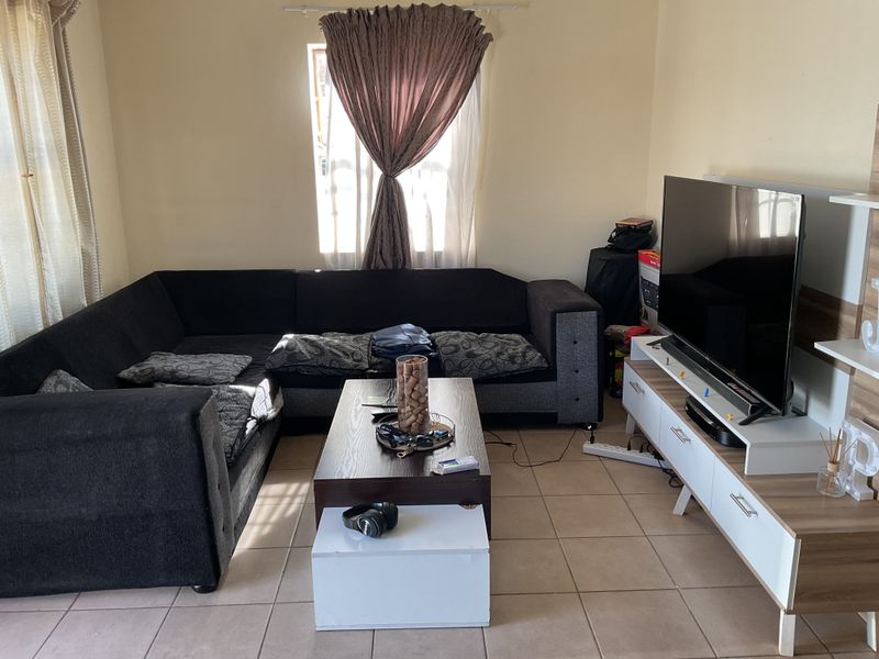 A functional living room featuring tiled flooring and natural light from a window, providing a comfortable space for relaxation.