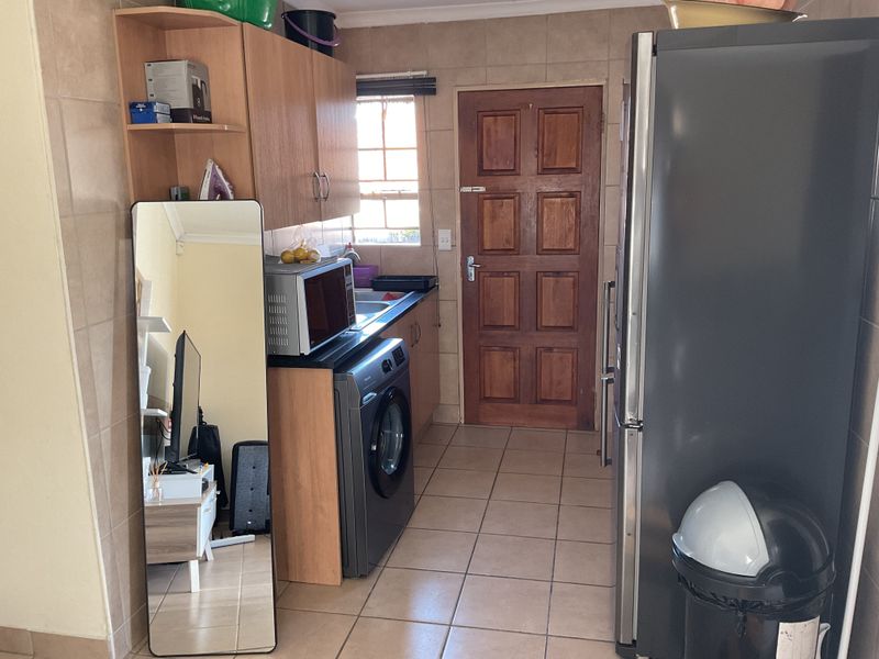 A functional laundry area featuring tiled walls and flooring, built-in cabinetry, and a solid wood exterior door.