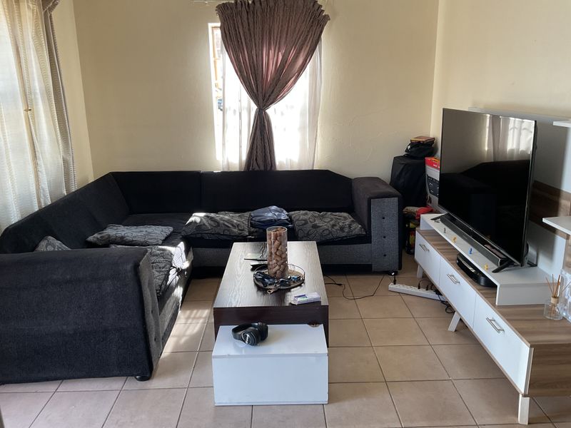A functional living room featuring tiled flooring and natural light from a window, providing a comfortable space for relaxation.