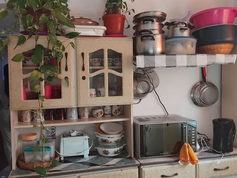 A dated kitchen area featuring built-in cabinetry, laminate countertops, and a built-in microwave, providing functional storage and prep space.