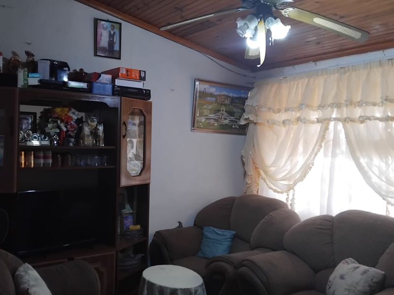A living room featuring a timber-clad ceiling and a central ceiling fan, providing a traditional aesthetic.