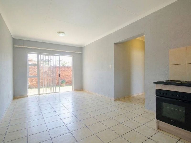 An open-plan living area featuring tiled flooring, a built-in oven and hob, and a sliding glass door providing access to the rear exterior.