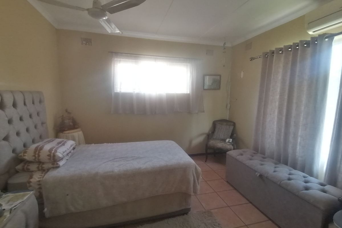 A bedroom featuring tiled flooring, a ceiling fan, and a wall-mounted split-system air conditioner.