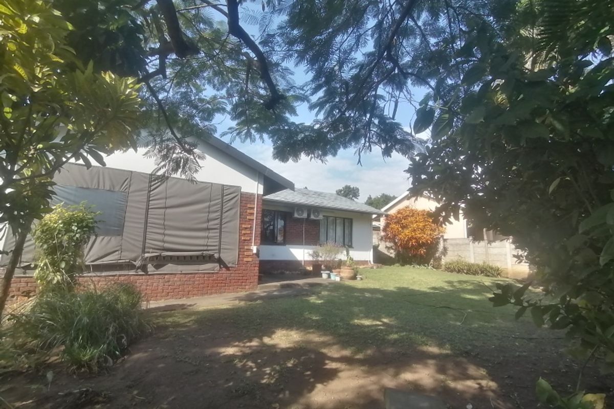 Rear view of the house featuring a brick facade, outdoor canvas blinds, and a private garden area with a boundary wall.