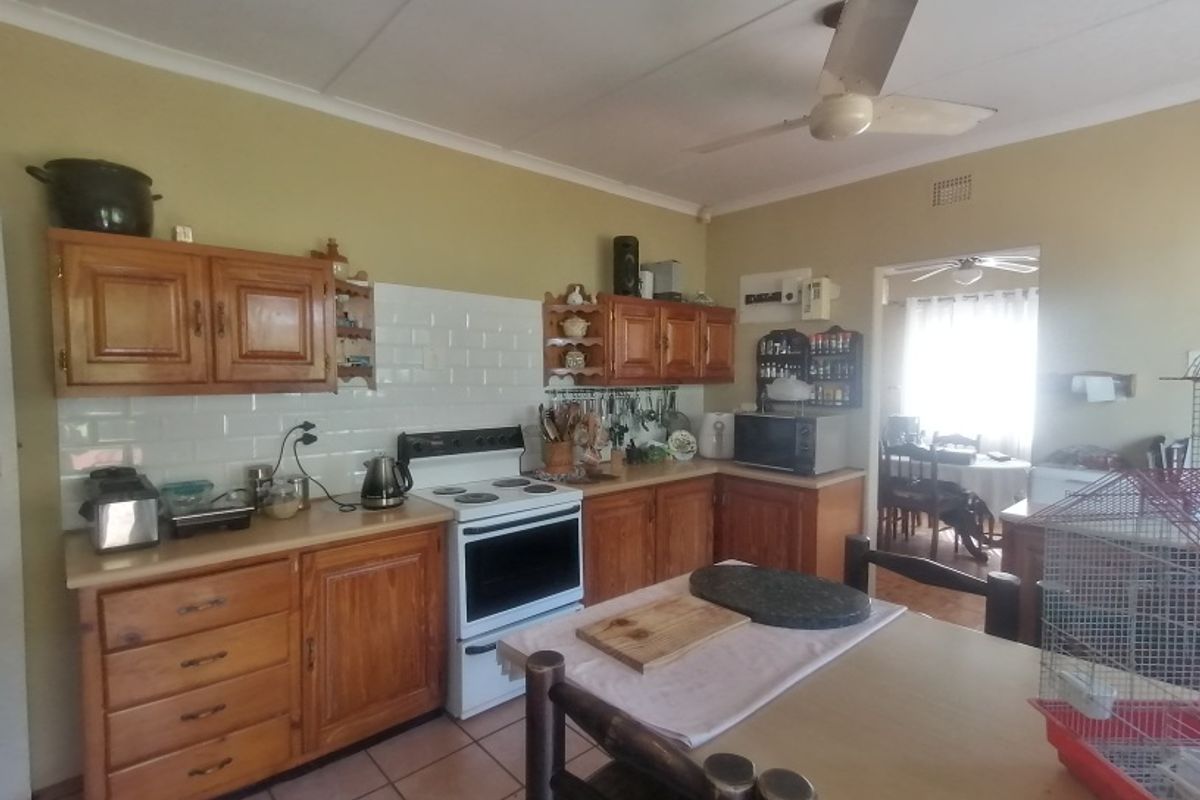 A functional kitchen featuring wooden cabinetry, a subway tile backsplash, and a freestanding stove, with direct access to the adjacent dining area.