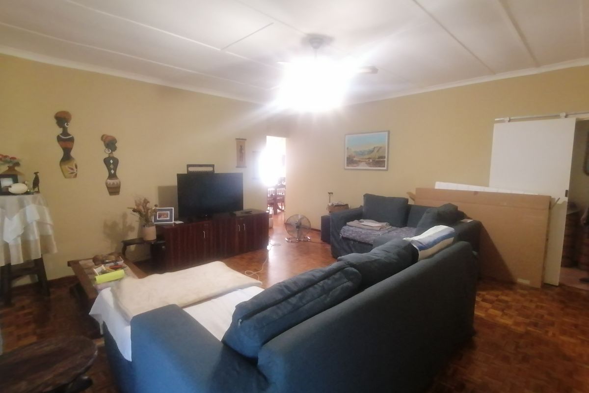 A living room featuring parquet flooring and a ceiling fan, providing a functional space with potential for modernization.