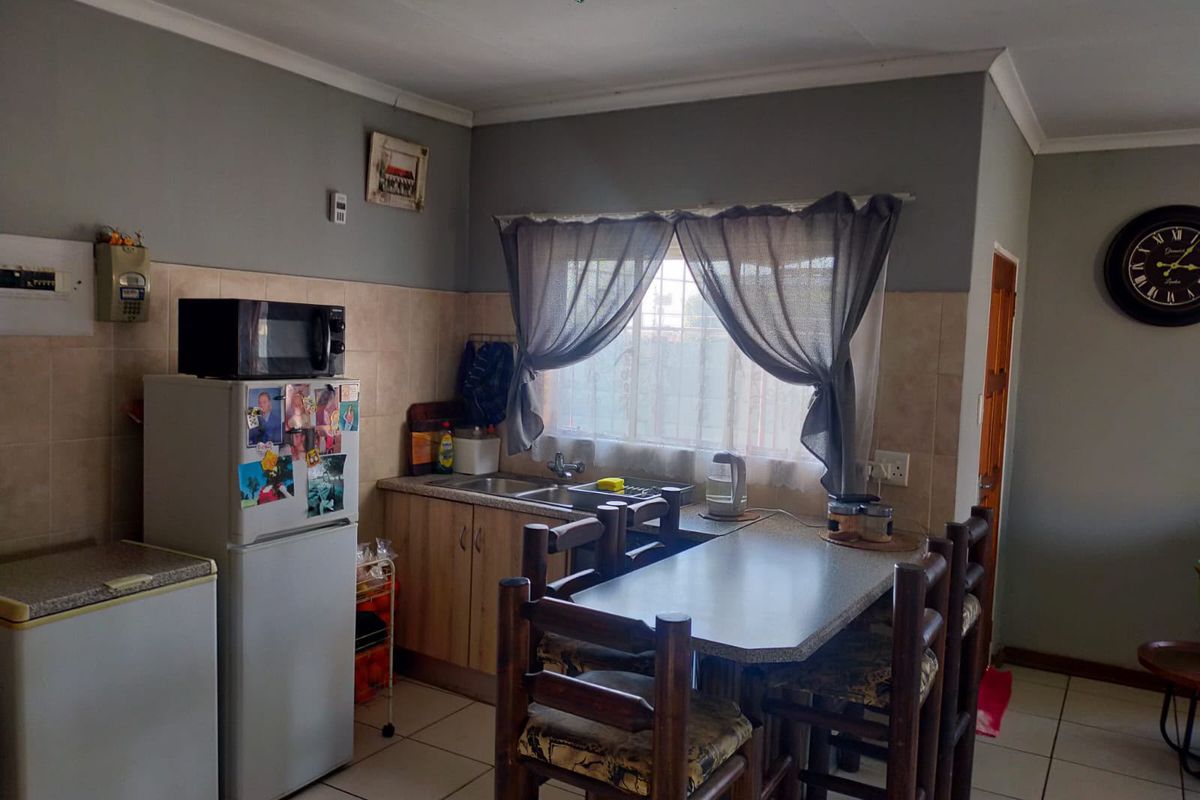 A functional kitchen featuring tiled flooring, built-in cabinetry, a stainless steel sink, and a tiled backsplash, providing a practical workspace.