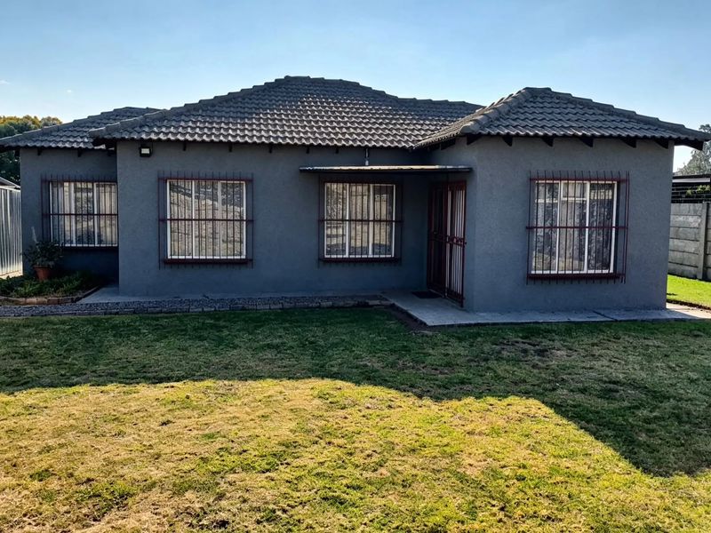 A view of the rear elevation of the house featuring a tiled roof, grey exterior finish, and security bars on the windows.