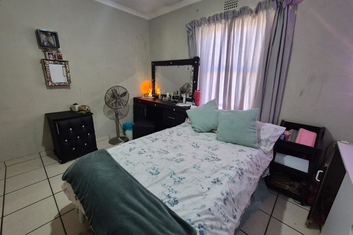 A bedroom featuring tiled flooring and a window with curtain rails. The room requires cosmetic updates to the wall finishes.
