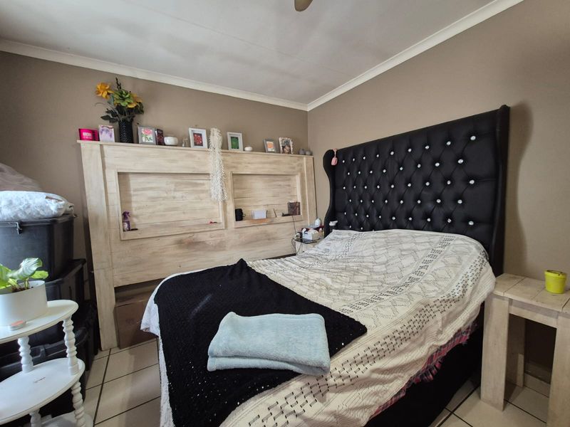 A bedroom featuring tiled flooring and a custom built-in wooden headboard unit with integrated shelving.