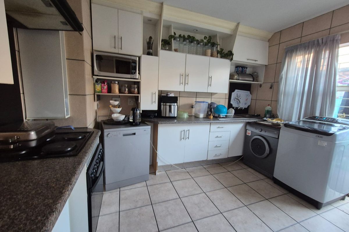 A functional kitchen featuring white cabinetry, laminate countertops, tiled backsplash, and ceramic flooring, providing a practical workspace with integrated appliance housing.