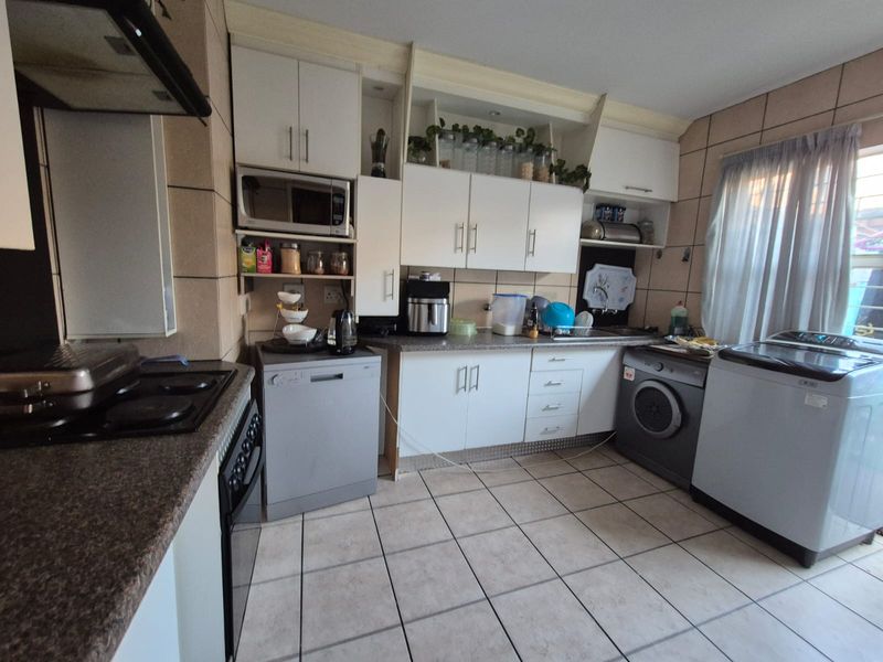 A functional kitchen featuring white cabinetry, laminate countertops, tiled backsplash, and ceramic flooring, providing a practical workspace with integrated appliance housing.