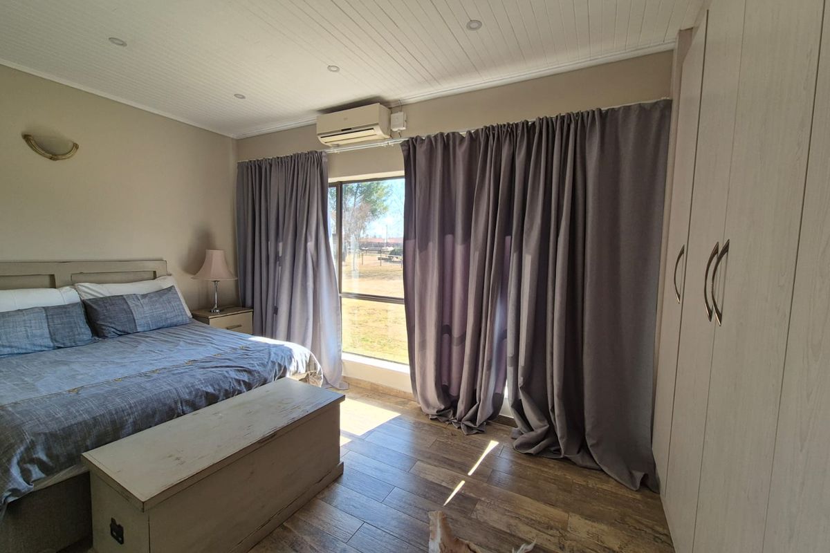 A well-maintained bedroom featuring tiled flooring, built-in cupboards, a split-system air conditioner, and a tongue and groove ceiling with recessed lighting.