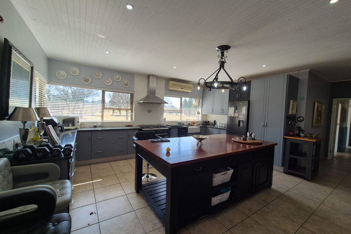 Spacious kitchen featuring a large central island with a wooden countertop, ample cabinetry, modern appliances, and tiled flooring throughout.