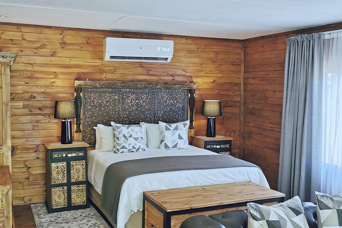 A cozy bedroom featuring warm timber wall cladding, a wall-mounted split-system air conditioner, and recessed ceiling lighting.