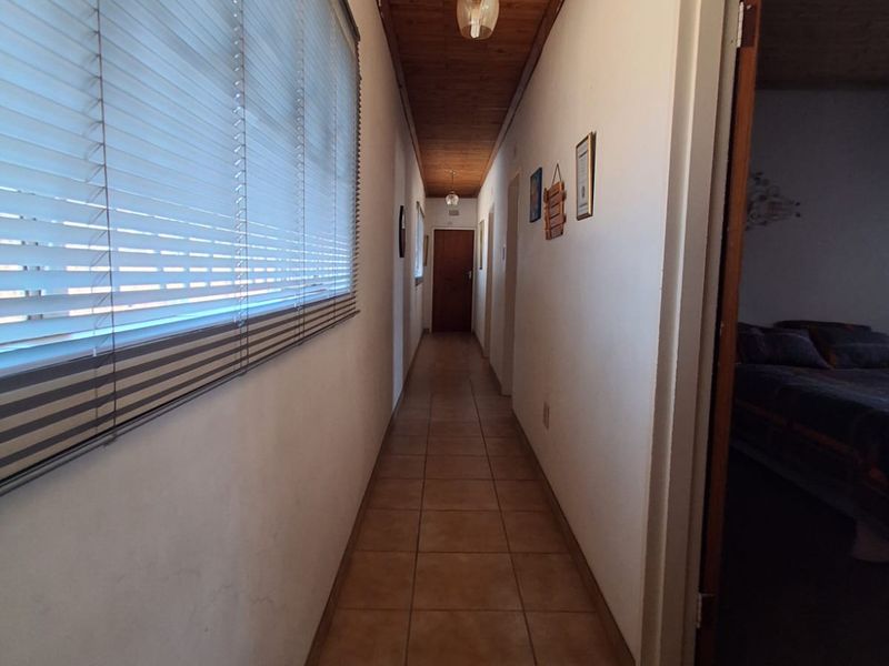 A long hallway featuring tiled flooring and a timber tongue and groove ceiling, providing access to adjacent rooms.