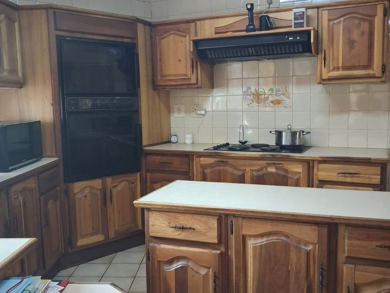 A traditional kitchen featuring extensive wooden cabinetry, built-in oven, extractor fan, and tiled backsplash, offering a functional layout with potential for modern updates.