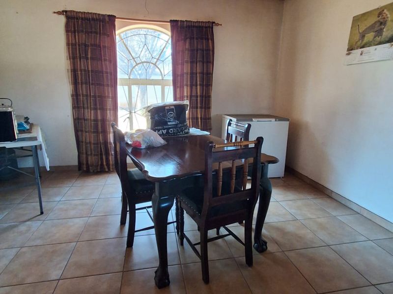 Dining room featuring ceramic floor tiles, a timber-clad ceiling, and a distinctive arched window, providing a functional space for meals.