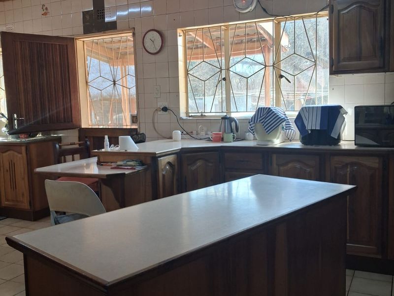A dated kitchen featuring wooden cabinetry, laminate countertops, tiled backsplash, and a timber ceiling, offering significant potential for a modern renovation.