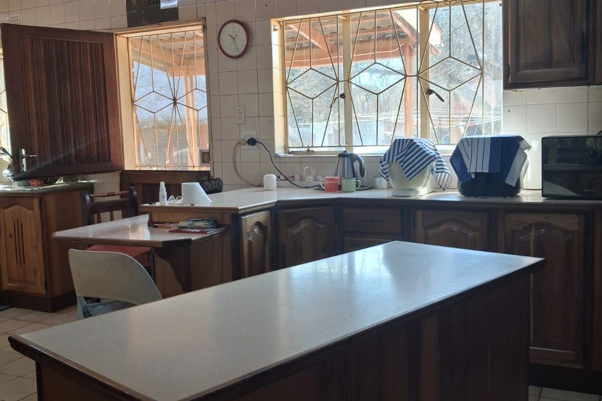 A dated kitchen featuring wooden cabinetry, laminate countertops, tiled backsplash, and a timber ceiling, offering significant potential for a modern renovation.