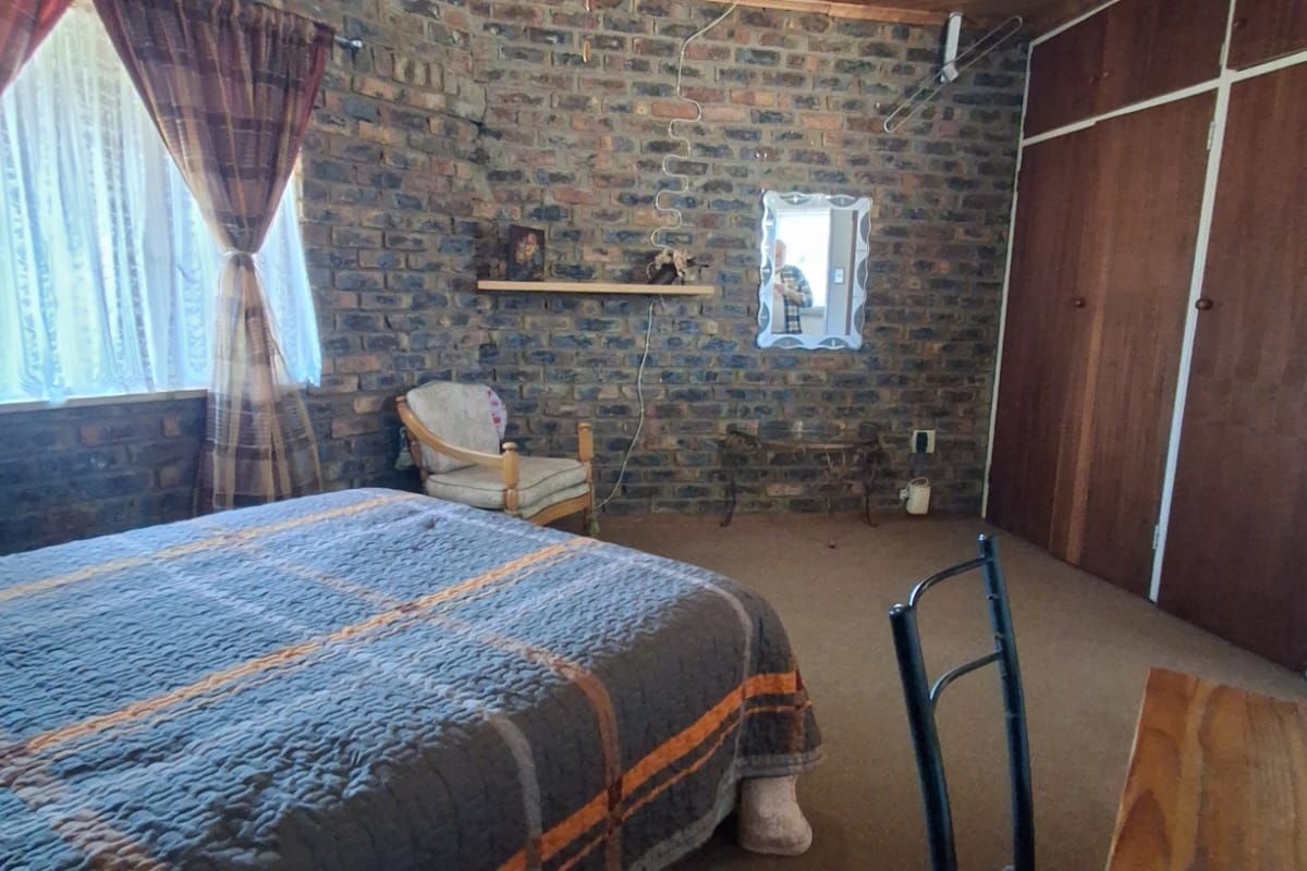 Bedroom featuring exposed brick walls, timber ceiling, ceiling fan, and built-in wooden cupboards.