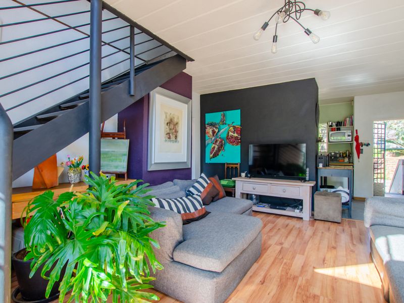 Open plan living area featuring a modern metal staircase, laminate flooring, and direct access to a rear utility space.