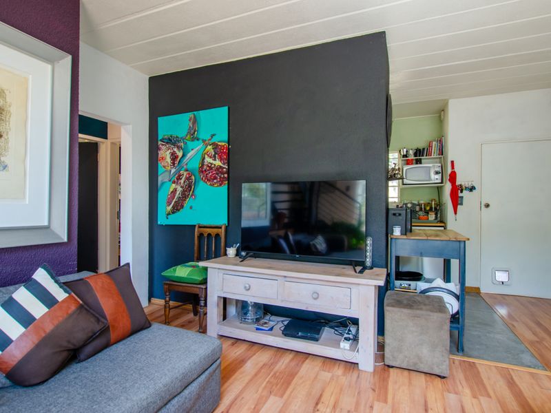 A living room area featuring laminate flooring and a neutral layout, with an adjacent transition space leading to a secondary area.