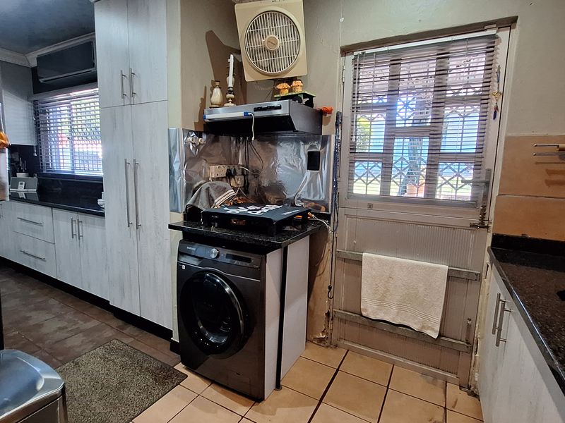 Kitchen featuring granite countertops, built-in cabinetry, and tiled flooring, with a security gate leading to the exterior.